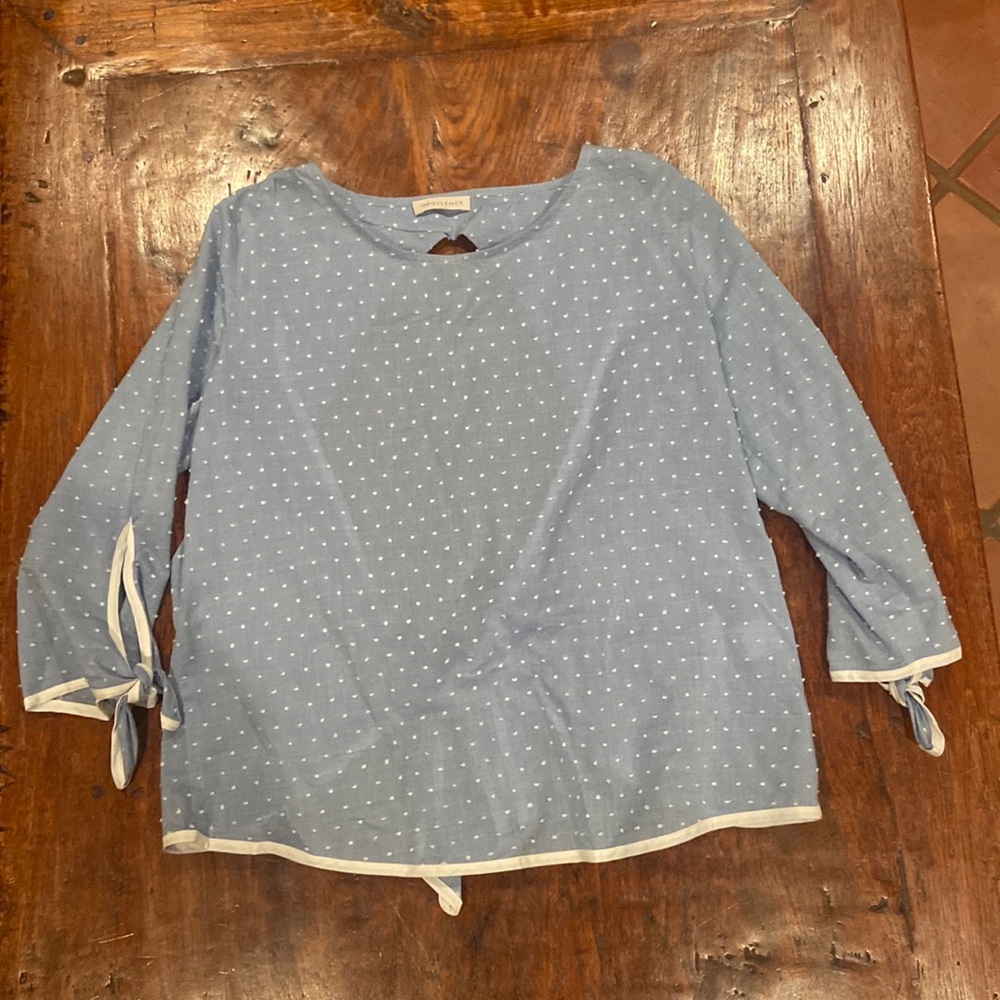 Such a pretty light blue top with an open tie back and raised polka dots.